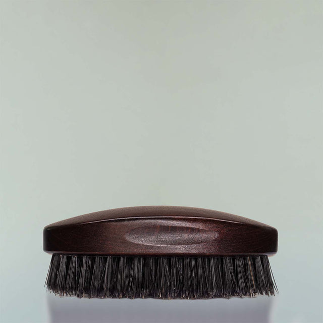 A Beardbrand 100% Boar’s Hair Oval Brush side view against a grey background.