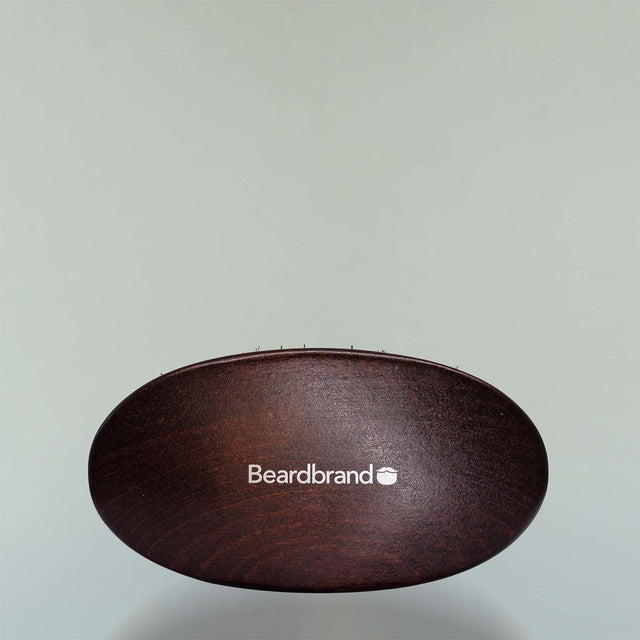 A Beardbrand 100% Boar’s Hair Oval Brush top view against a grey background.