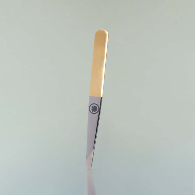 The slant tip Beardbrand Tweezers with two-tone stainless steel and the Beardbrand circle logo.